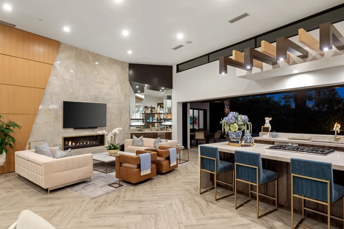 Open living room and kitchen with a linear fireplace, stone feature wall and marble island seating